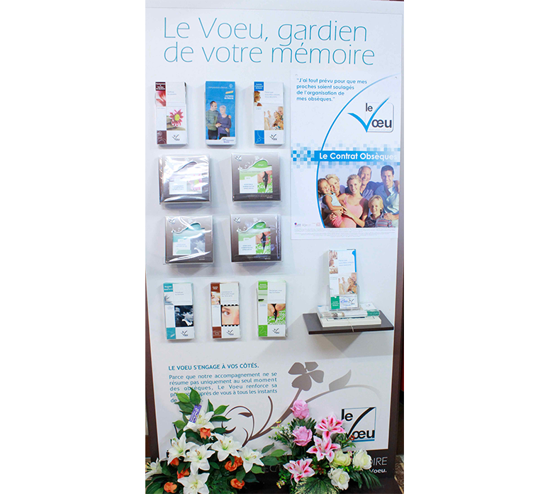 Présentoir pour produits souvenirs Voeu avec brochures et composition florale à la base
