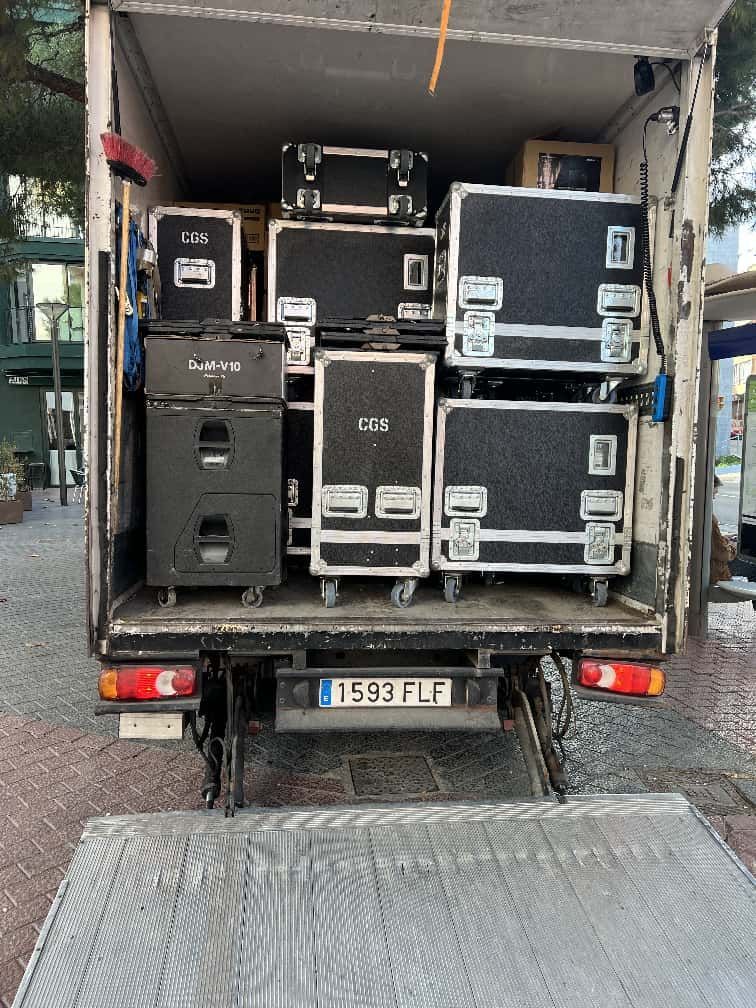 Una plataforma de camión llena de cajas con equipos de escenario, listas para cargar o descargar.