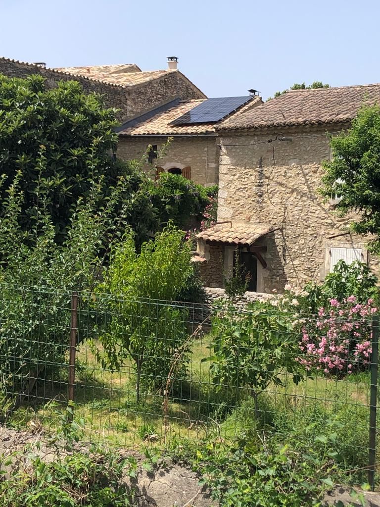 Une maison traditionnelle en pierres et panneaux solaires sur sa toiture.