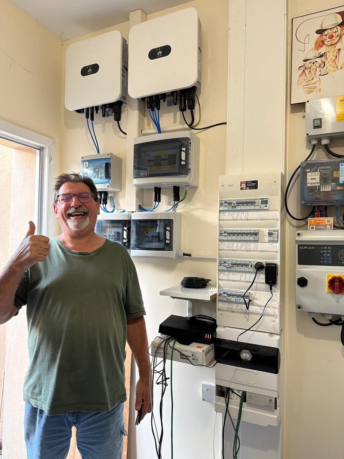 Un client souriant et le pouce en l'air devant son raccordement électrique aux panneaux solaires.