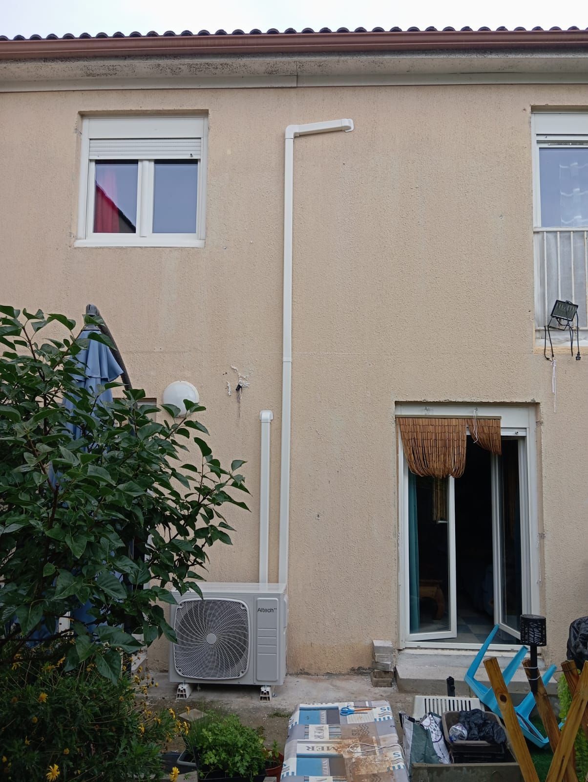 Une unité extérieure de PAC sur la façade d'une maison.