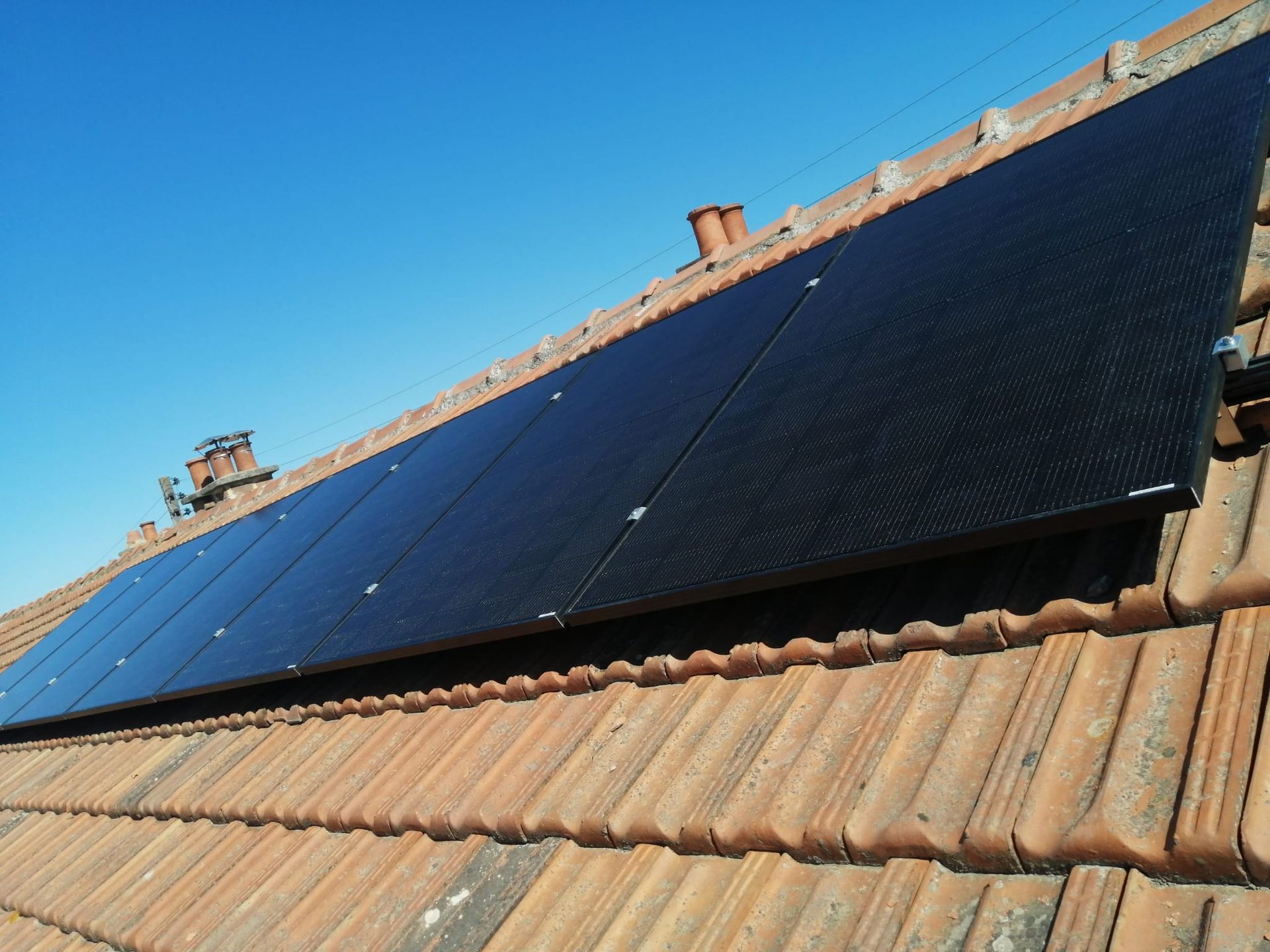 Plusieurs panneaux photovoltaïques sur un toit en tuiles.