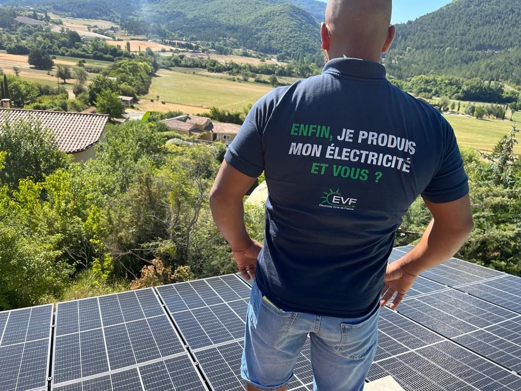 Un artisan de EVF sur un toit avec des panneaux solaires, portant un t-shirt estampillé du logo de l'entreprise.