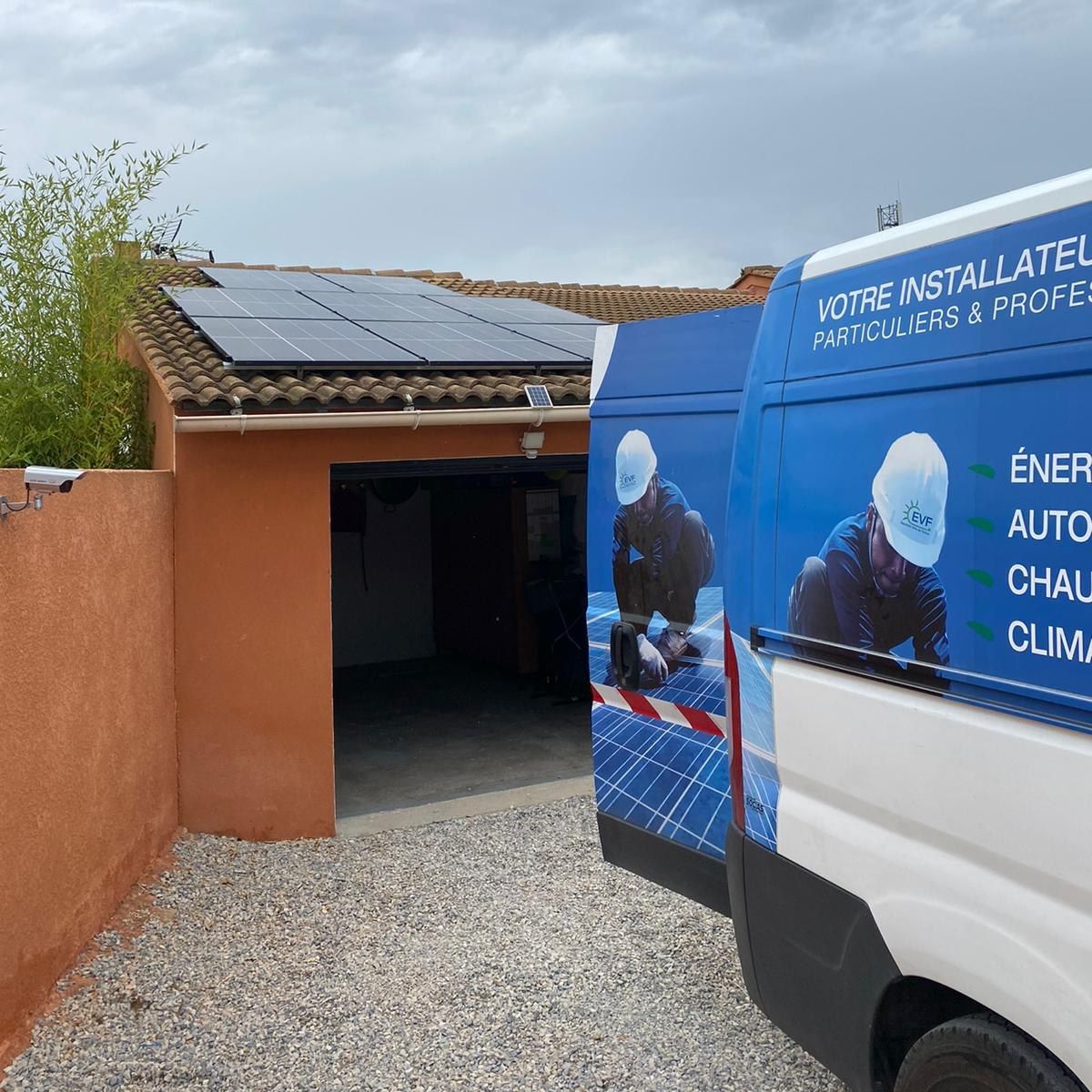 Un camion de la flotte de EVF devant un garage avec des panneaux solaires dessus.