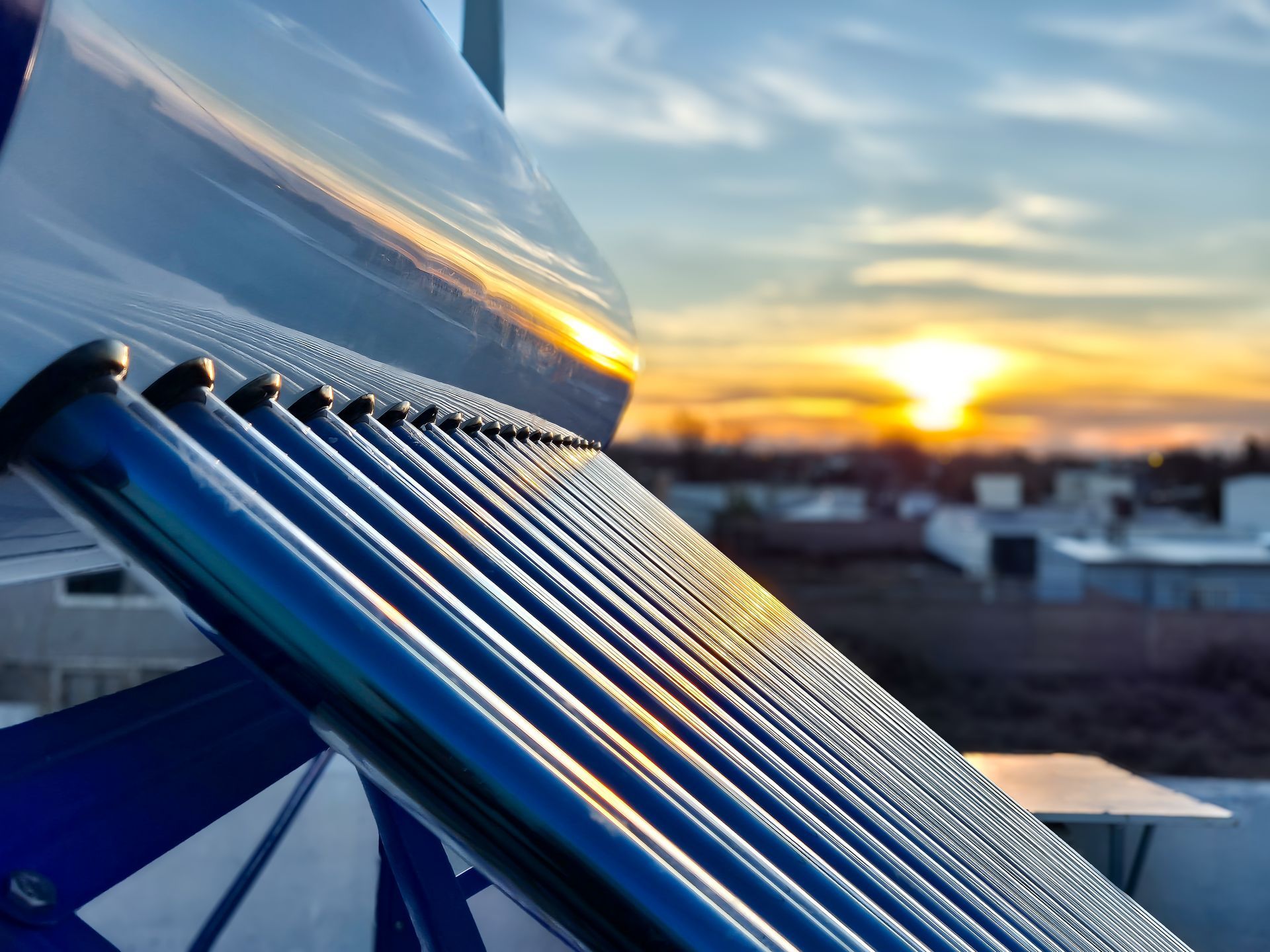 Vue rapprochée d'un chauffe-eau solaire sur fond de coucher de soleil.