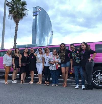 Un grupo de personas posa para una fotografía delante de una limusina rosa.