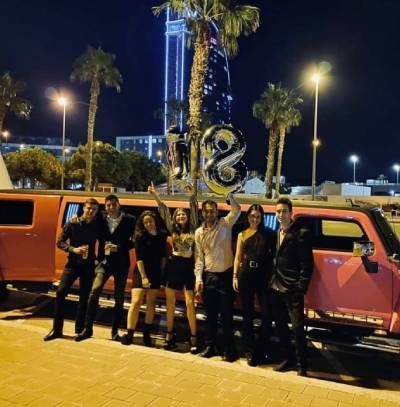 Un grupo de personas posa para una foto frente a una limusina que tiene el número 18.