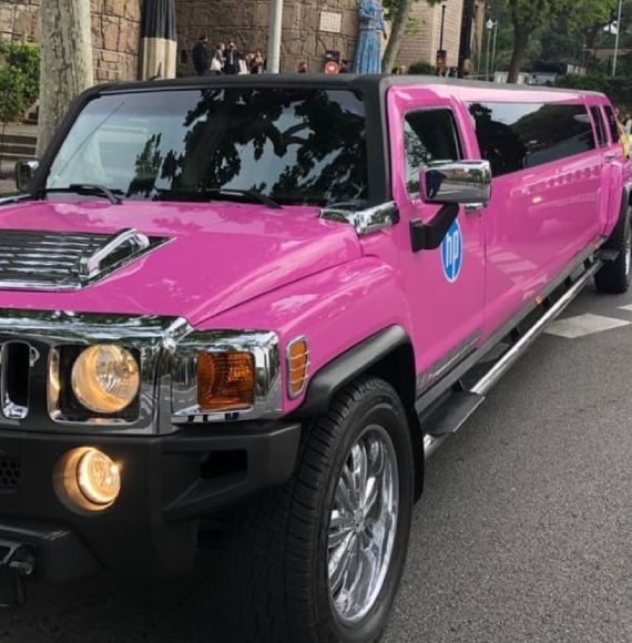 Un Hummer rosa está estacionado al costado de la carretera.
