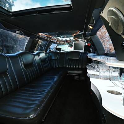 El interior de una limusina con asientos de cuero negro y un televisor de pantalla plana.