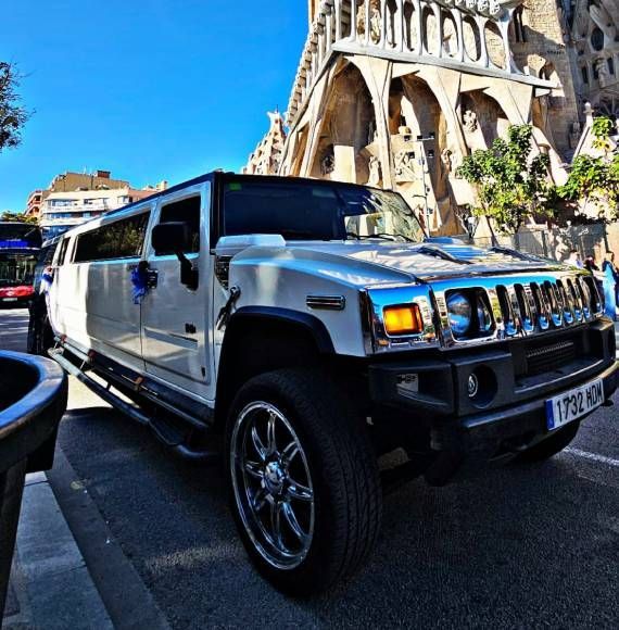Un Hummer blanco está estacionado frente a un edificio.