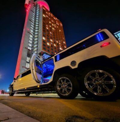 Una limusina está estacionada frente a un edificio alto por la noche.