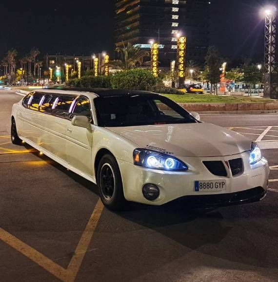 Una limusina blanca está estacionada en un estacionamiento por la noche.