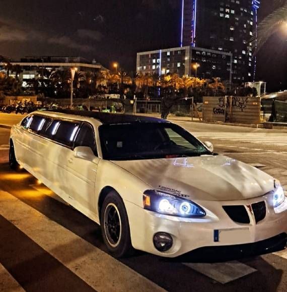 Una limusina blanca está estacionada en un estacionamiento por la noche.