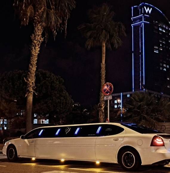 Una limusina blanca está estacionada frente a un hotel.