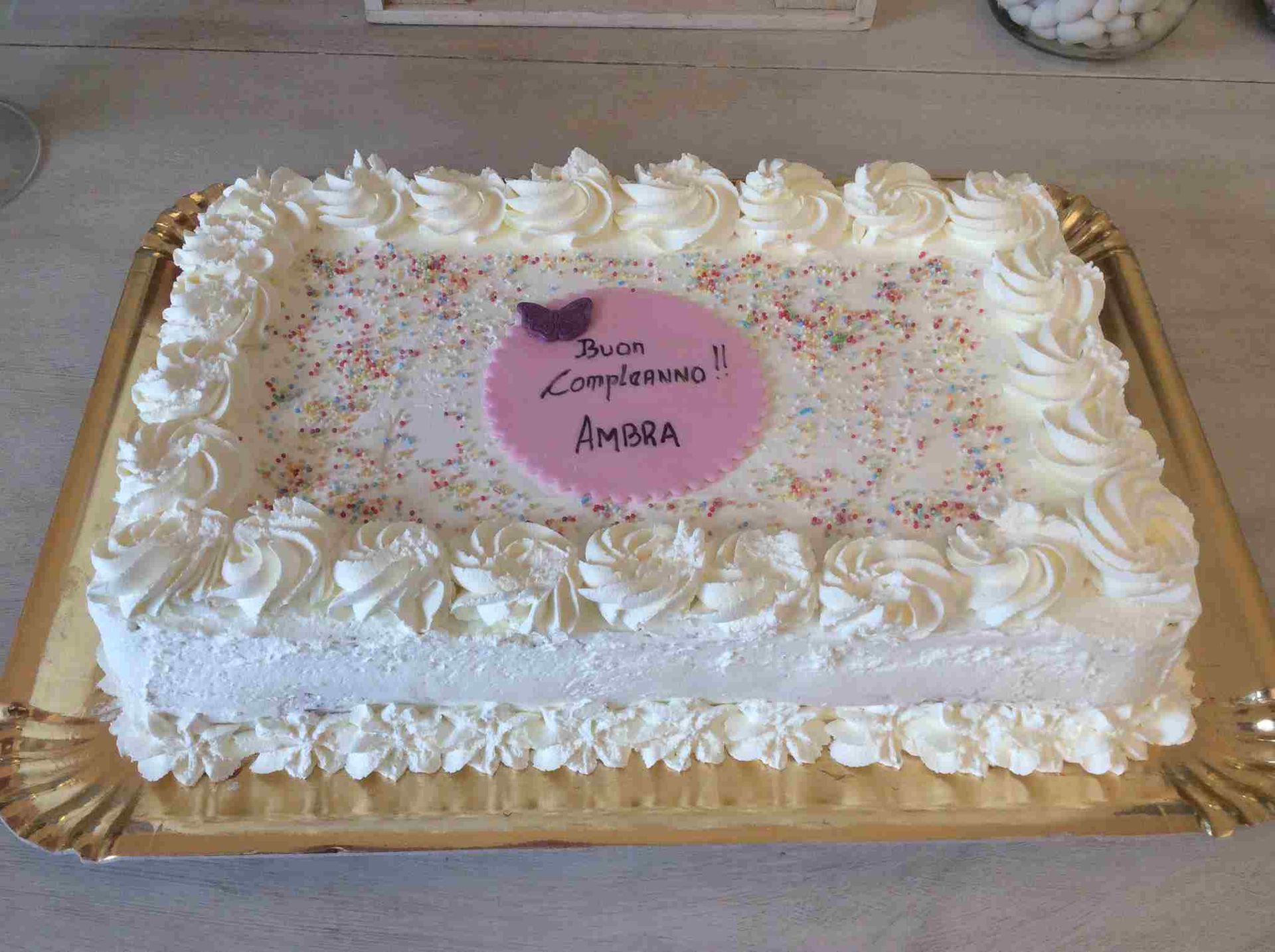 Una torta di compleanno con panna montata e granelli di zucchero su un vassoio.