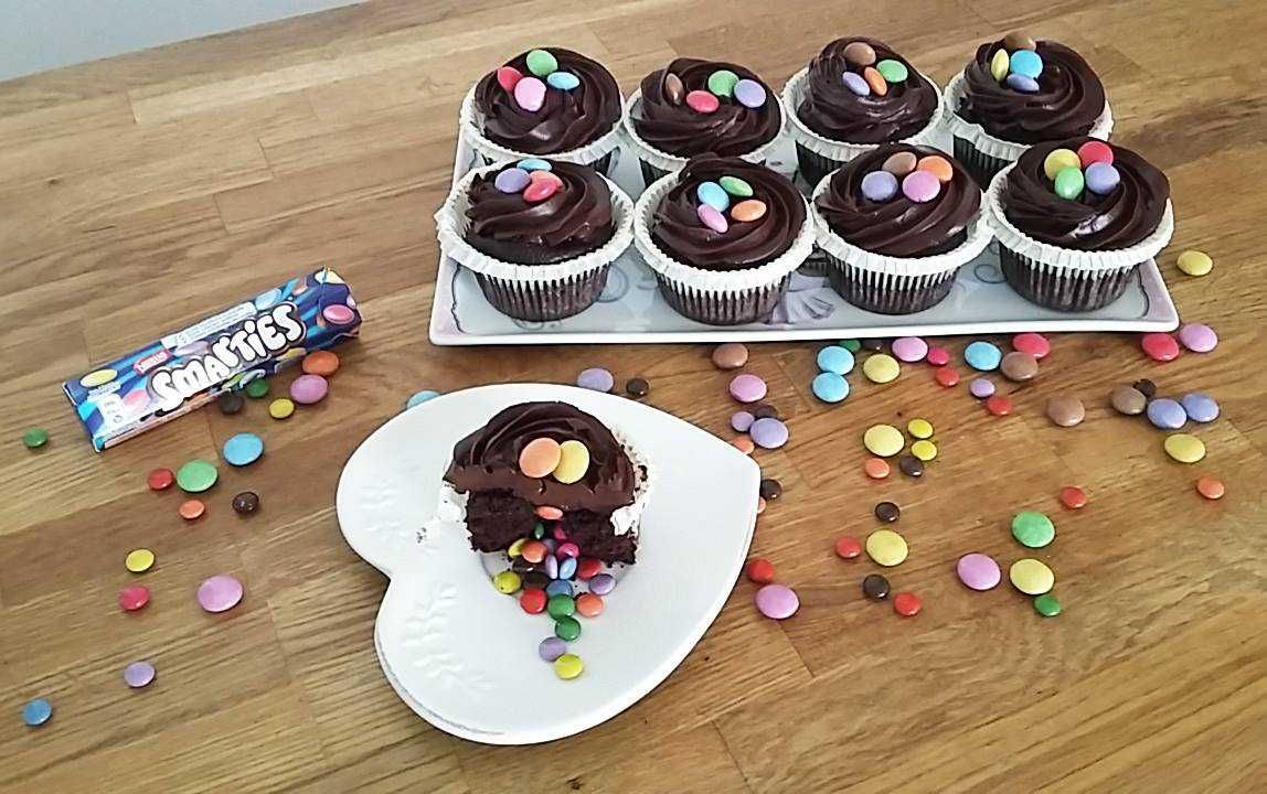 Un piatto bianco con un cupcake sopra accanto a un vassoio di cupcake.