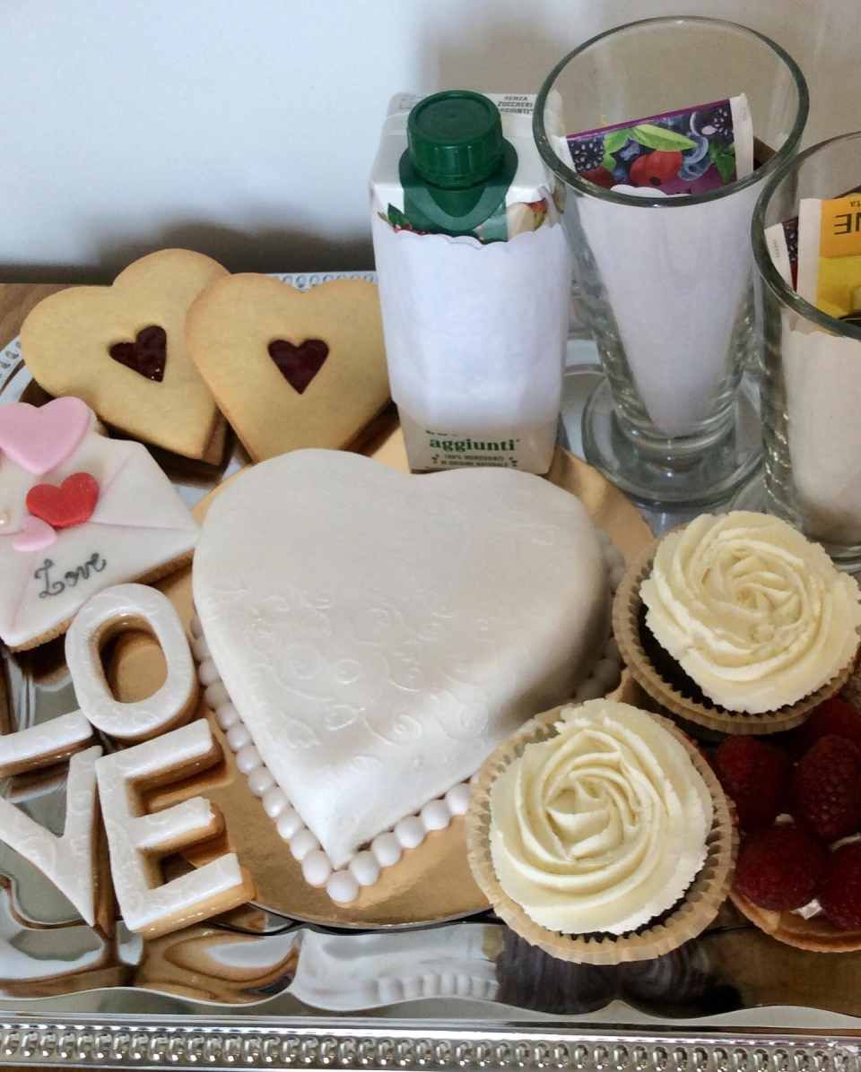 Una torta a forma di cuore è circondata da cupcake e biscotti