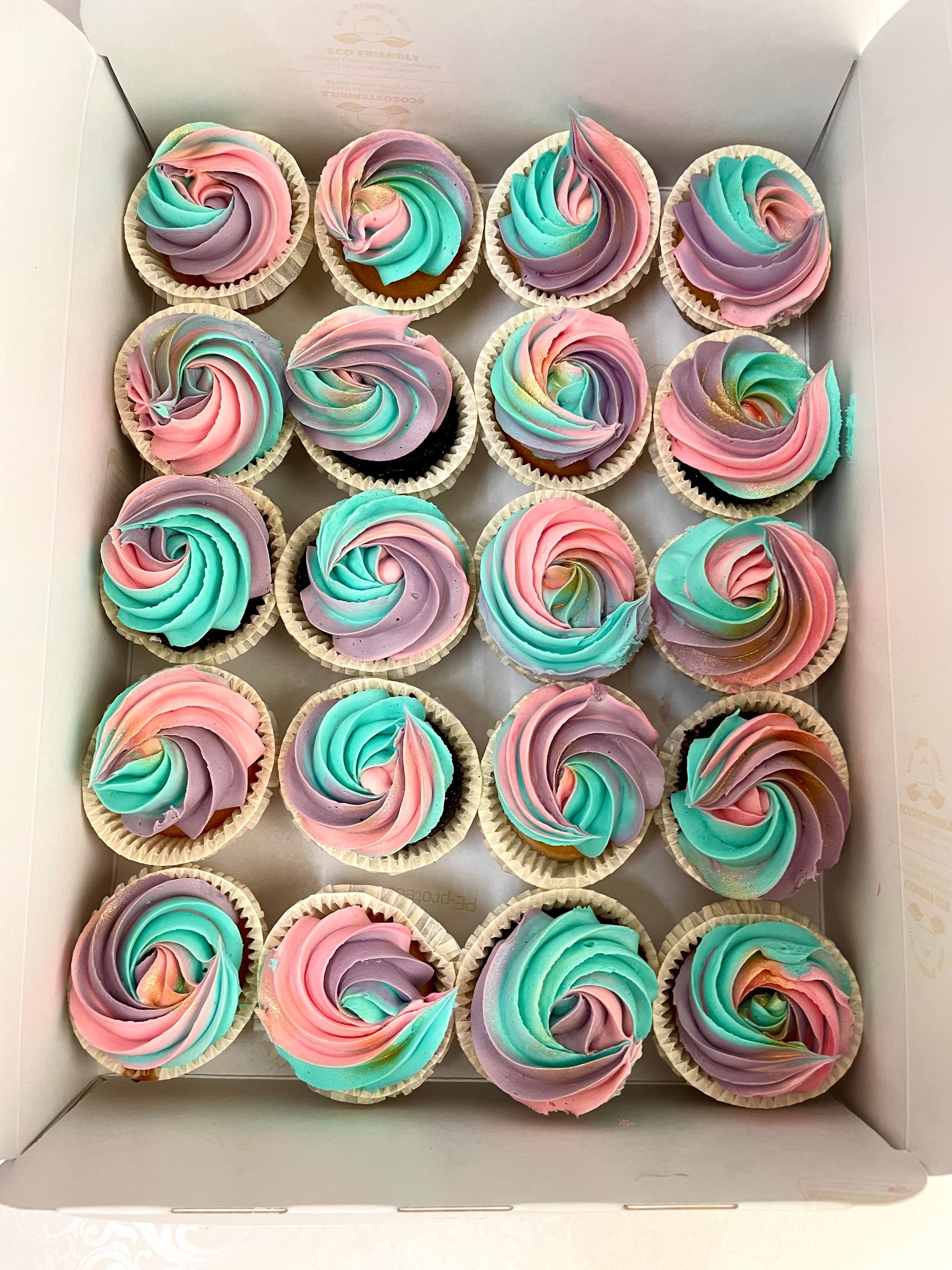 Una torta con una scarpa in cima e cupcakes con lo smalto sopra