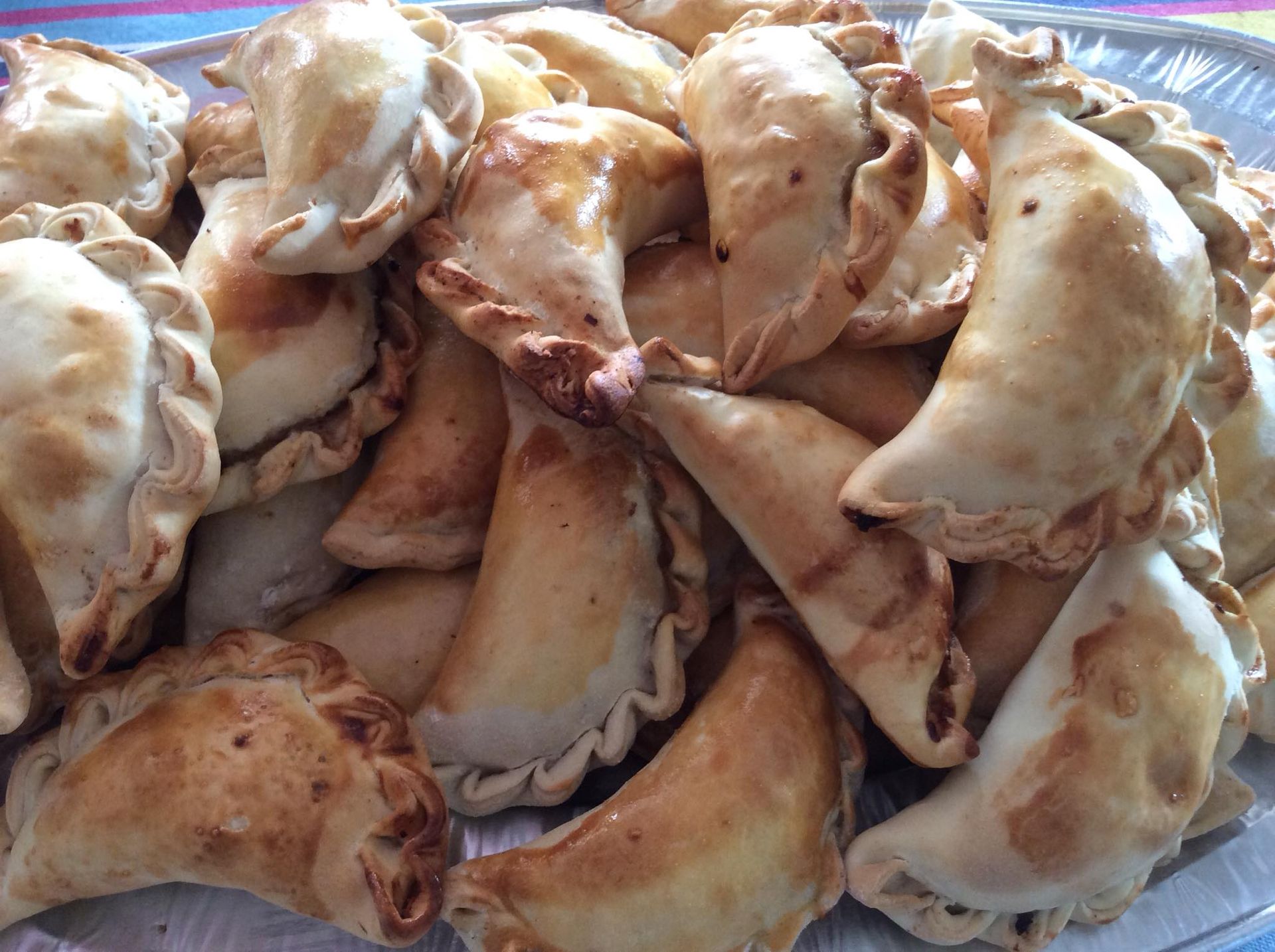 Un piatto di empanadas è appoggiato su un tavolo di legno.