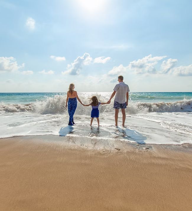 A family is walking on the beach holding hands.