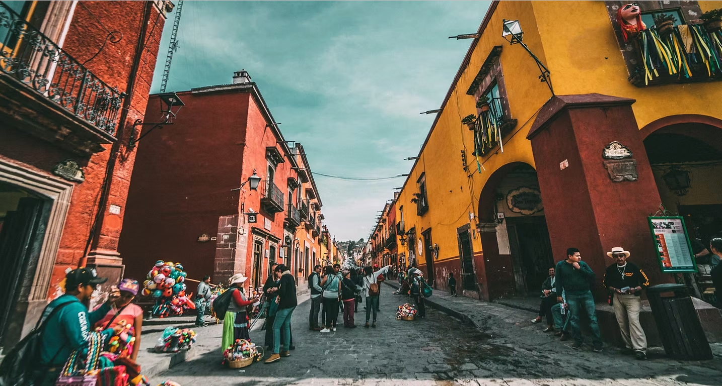 A group of people are walking down a street in front of a yellow building.