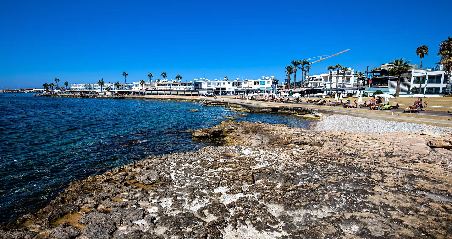 A beach with a lot of rocks and buildings in the background.