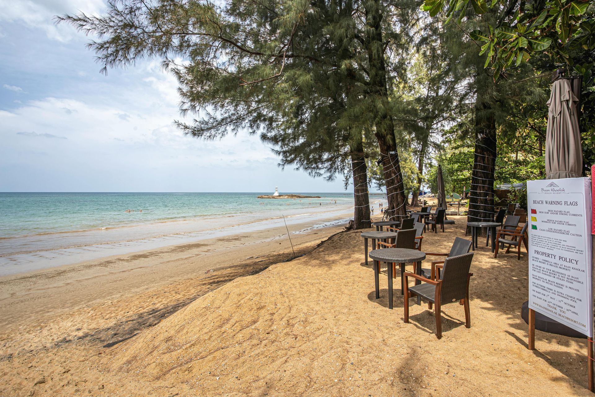 There are tables and chairs on the beach near the ocean.