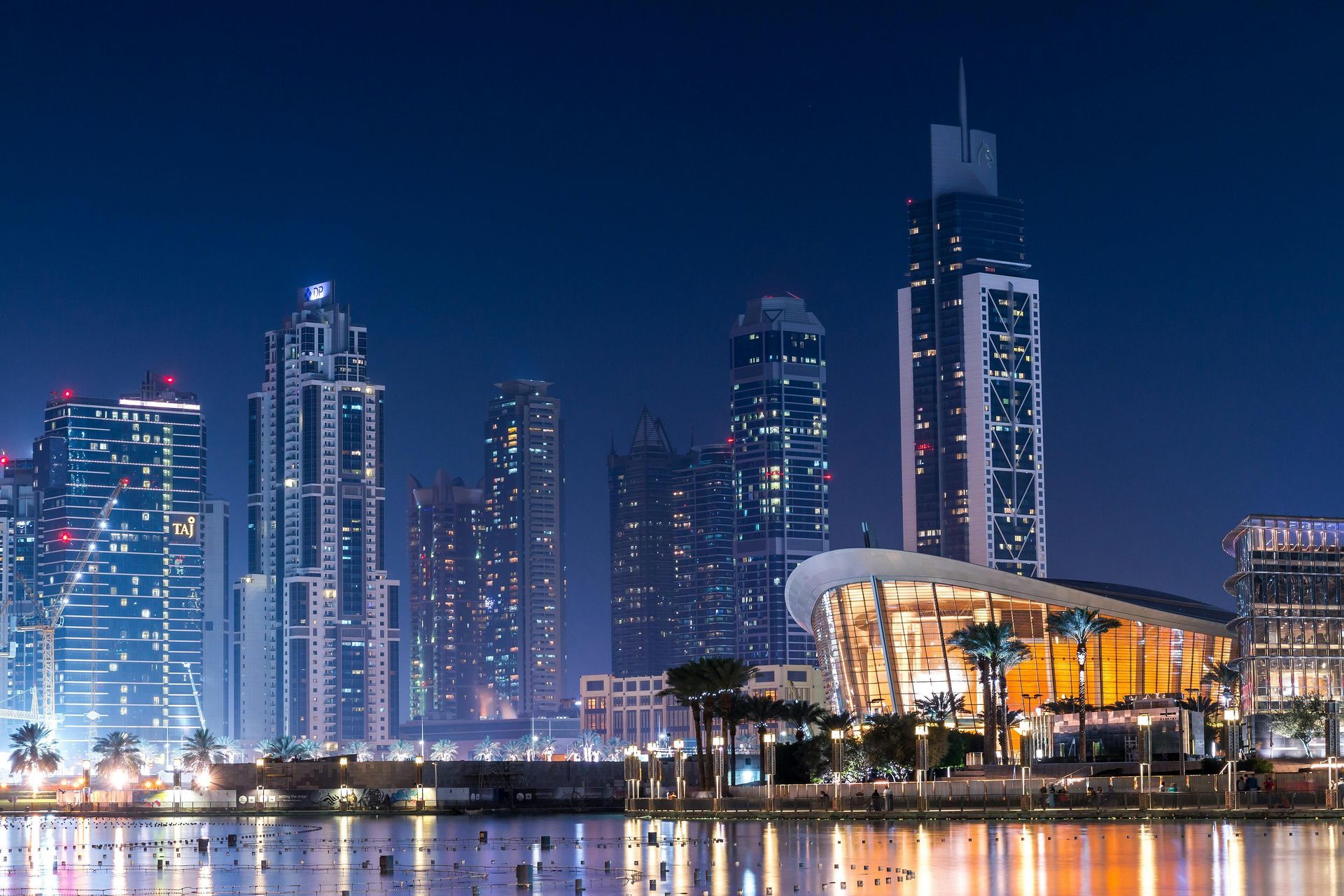A city skyline at night with a large body of water in the foreground.