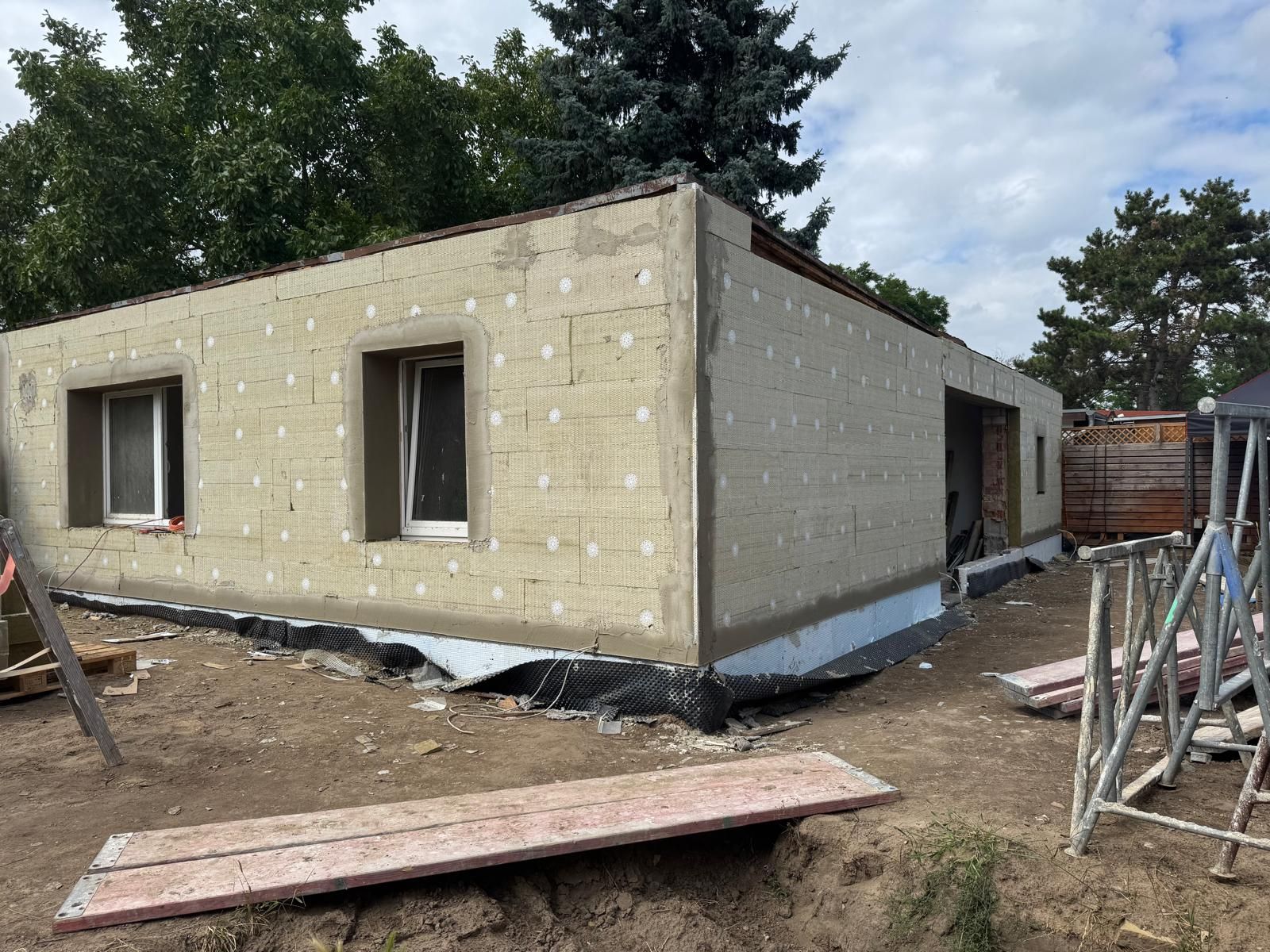 Person mit Handschuhen, die mit einem Spachtel Spachtelmasse auf eine Wand aufträgt.