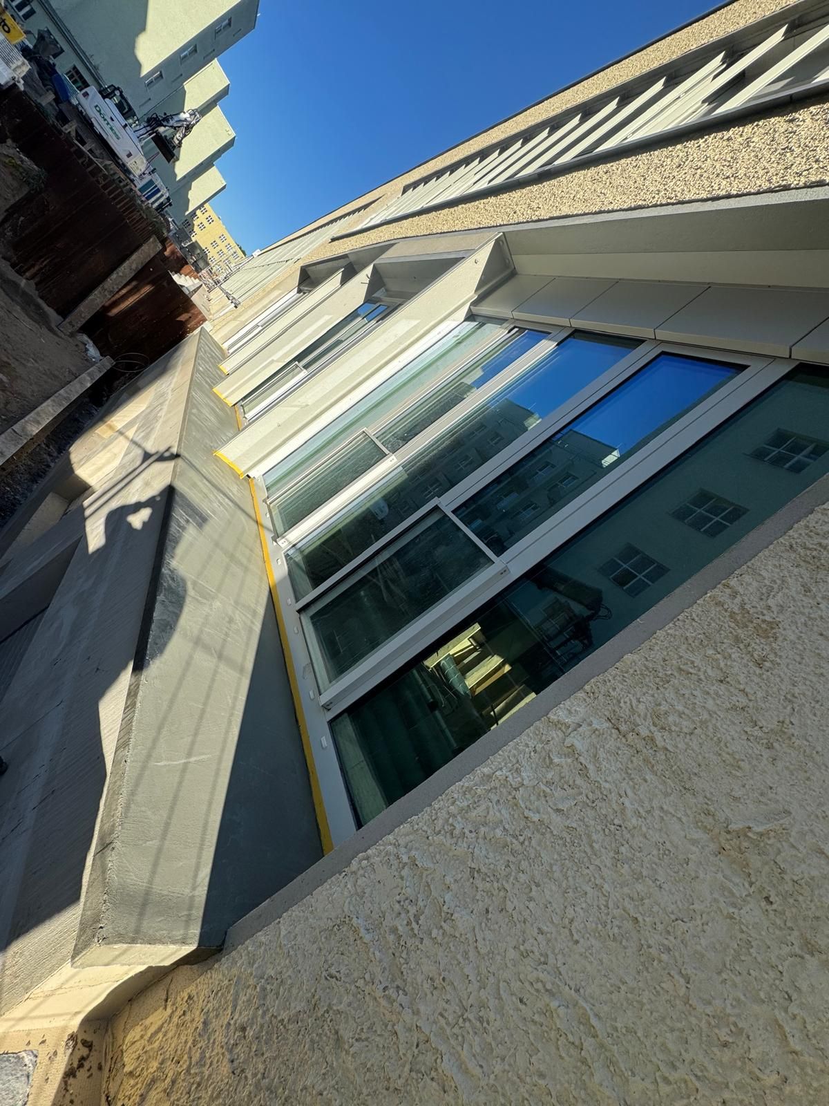 Person mit roten Handschuhen hält ein Spachtelmesser mit weißer Spachtelmasse und arbeitet an einer weißen Wand.