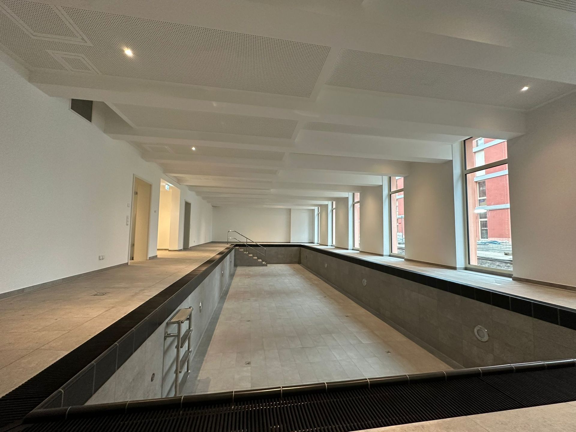 Person mit Handschuhen, die mit einem Spachtel Spachtelmasse auf eine Wand aufträgt.