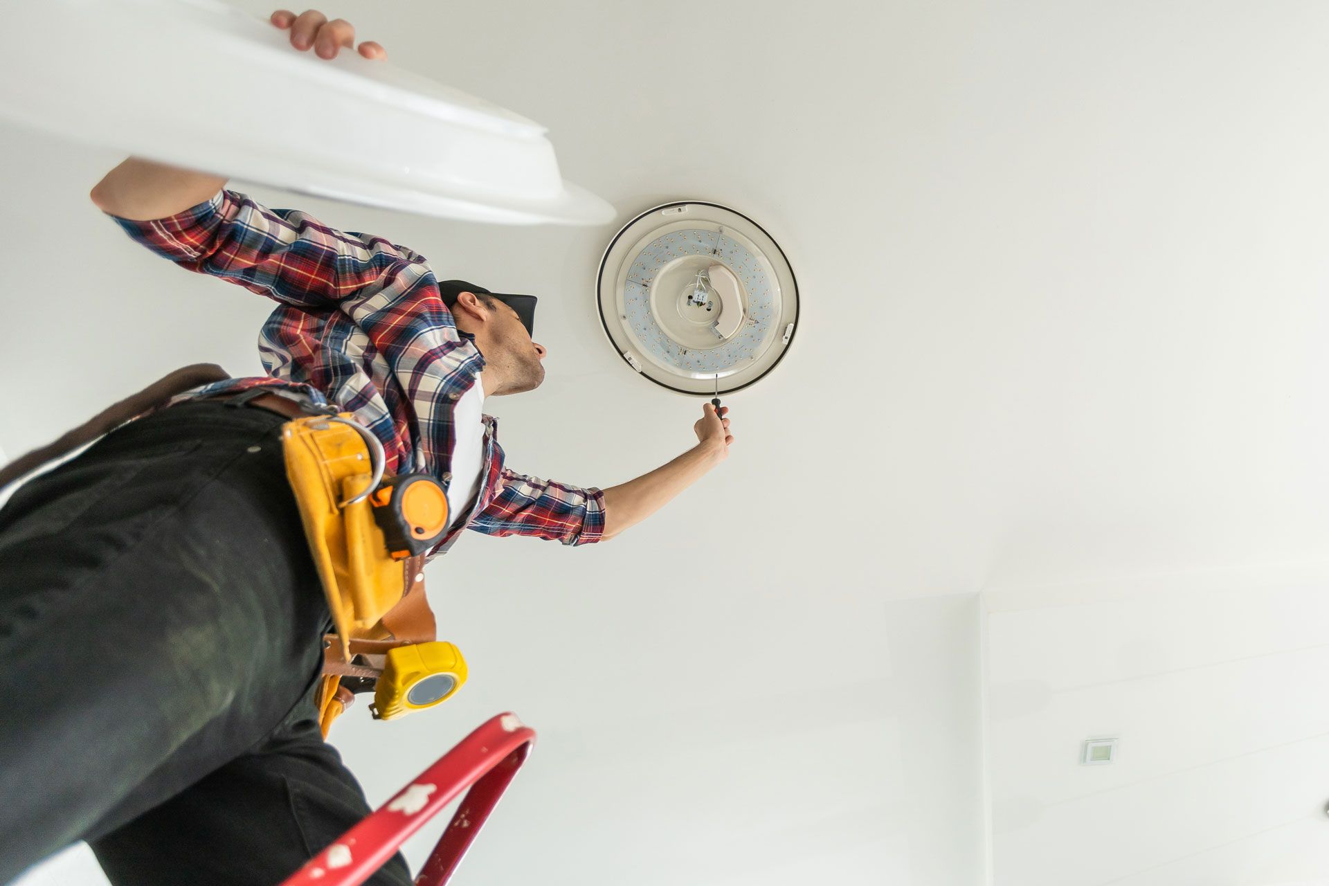 Vue en contre-plongée de l'installation d'un éclairage par un électricien