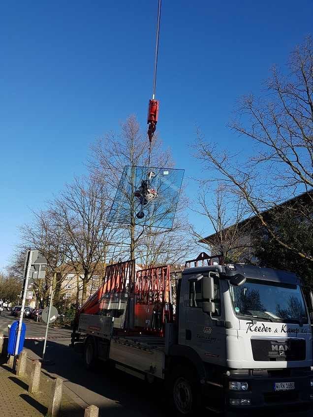 ein Kran mit Saugnäpfen hebt eine große Glasscheibe