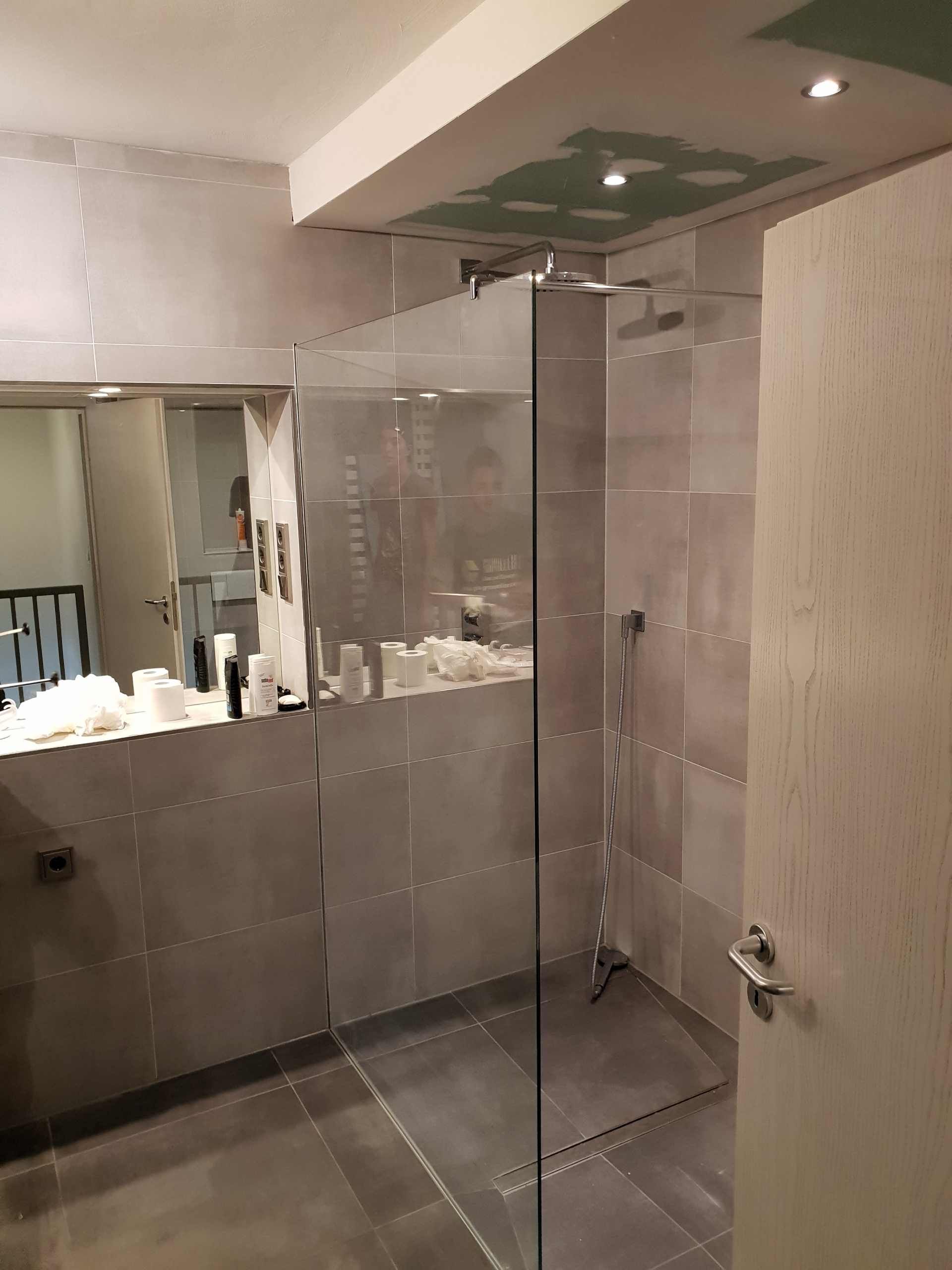 Ein Badezimmer mit Dusche, Glastür und Spiegel.