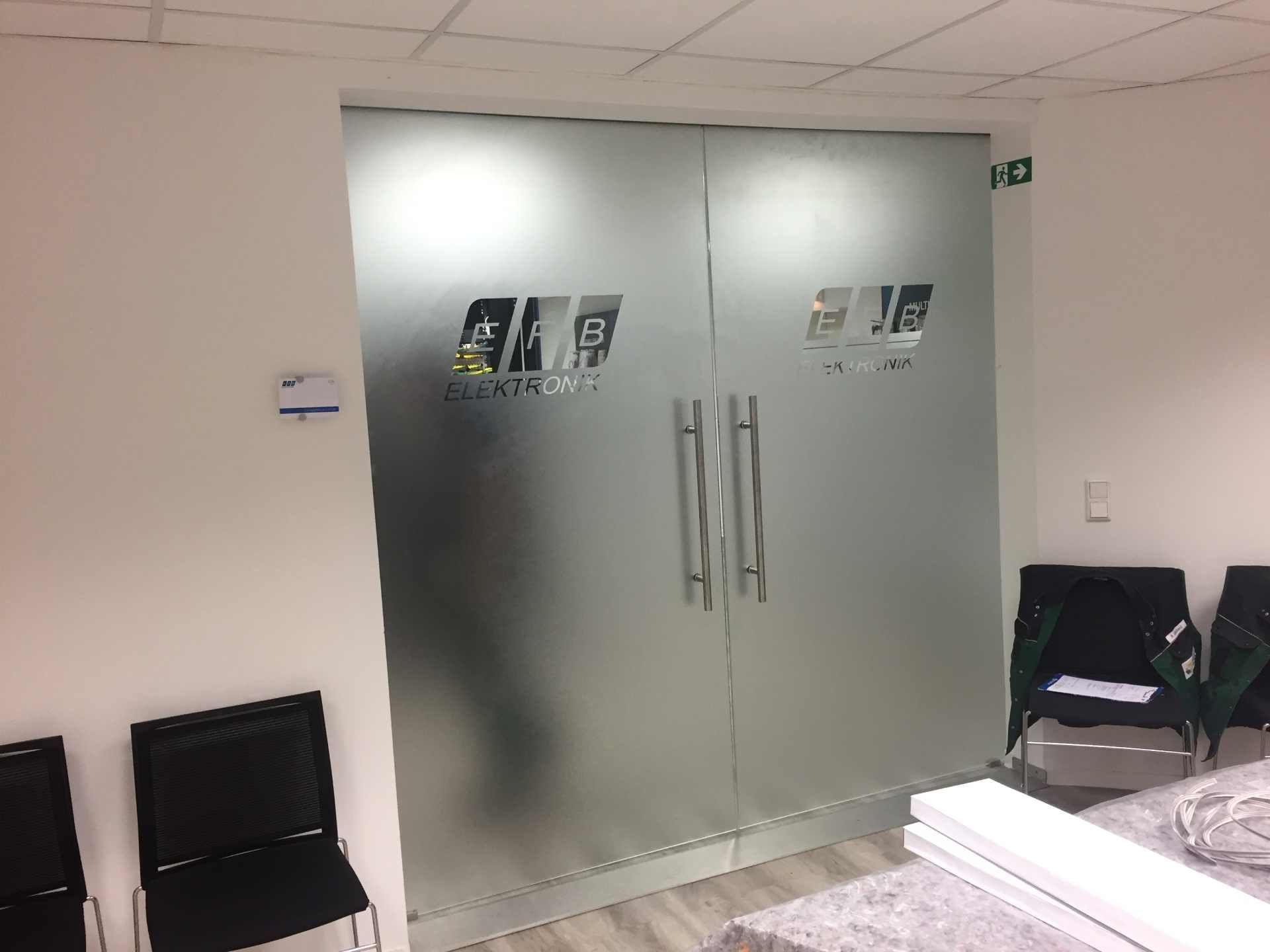 Ein Wartezimmer mit Stühlen und einer Milchglastür