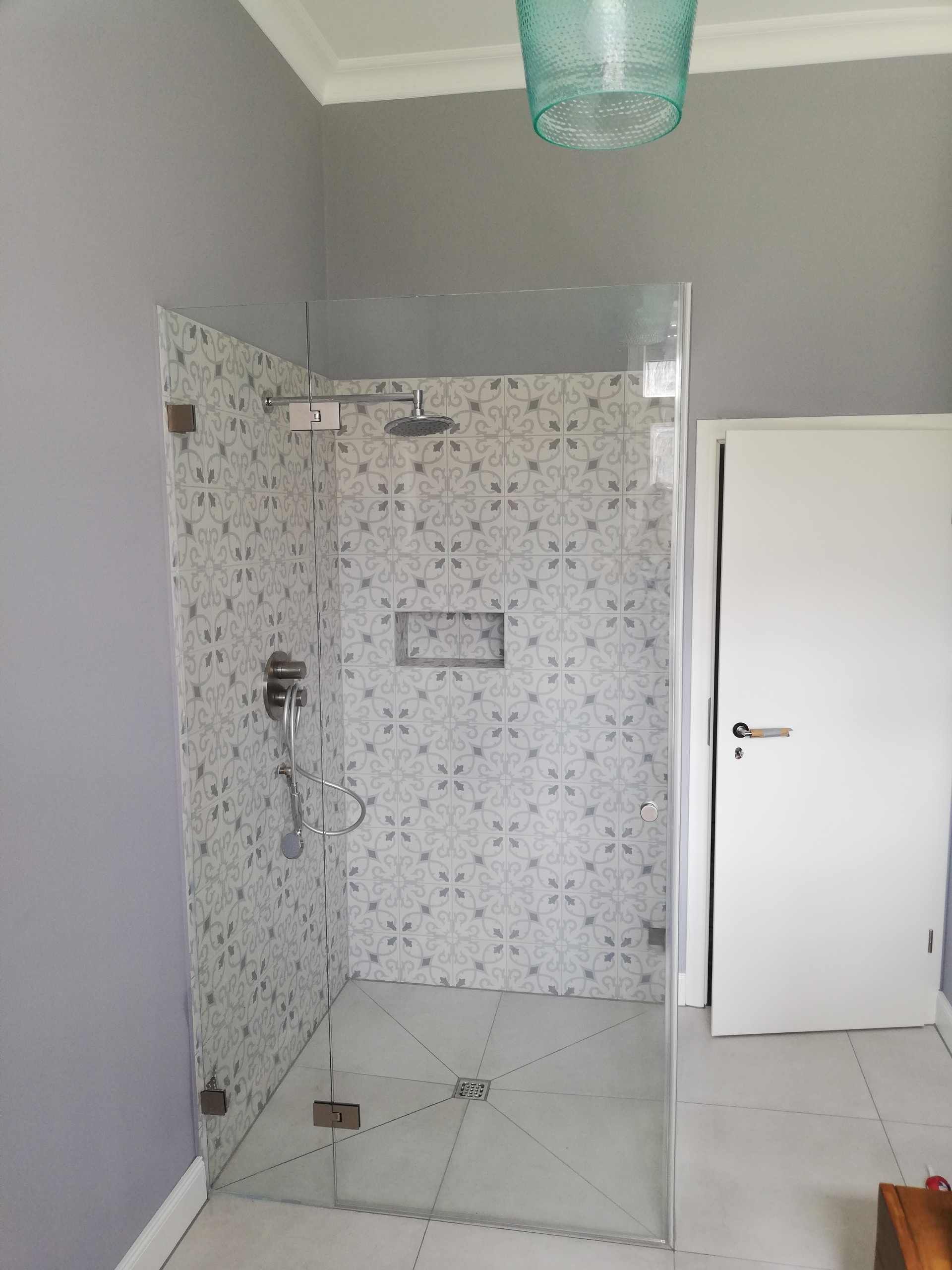 Ein Badezimmer mit ebenerdiger Dusche und Glastür.