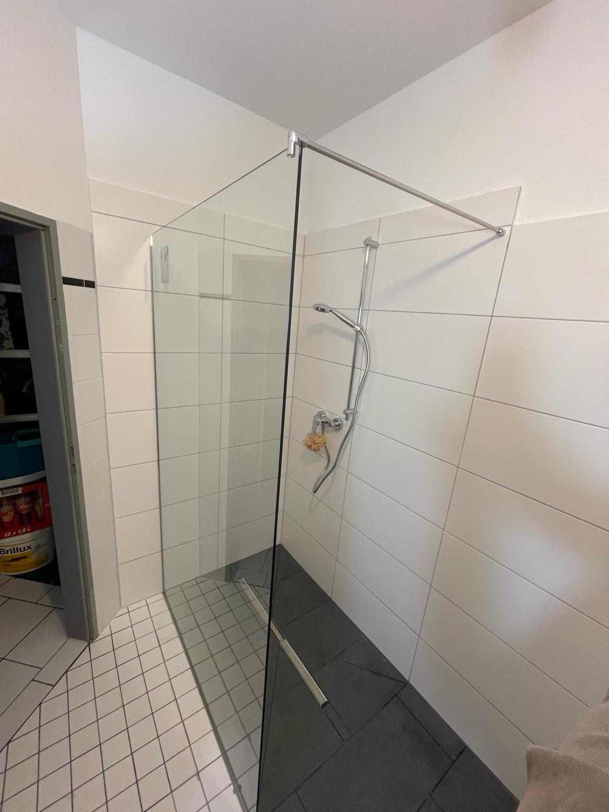 Ein Badezimmer mit ebenerdiger Dusche und Glastür.