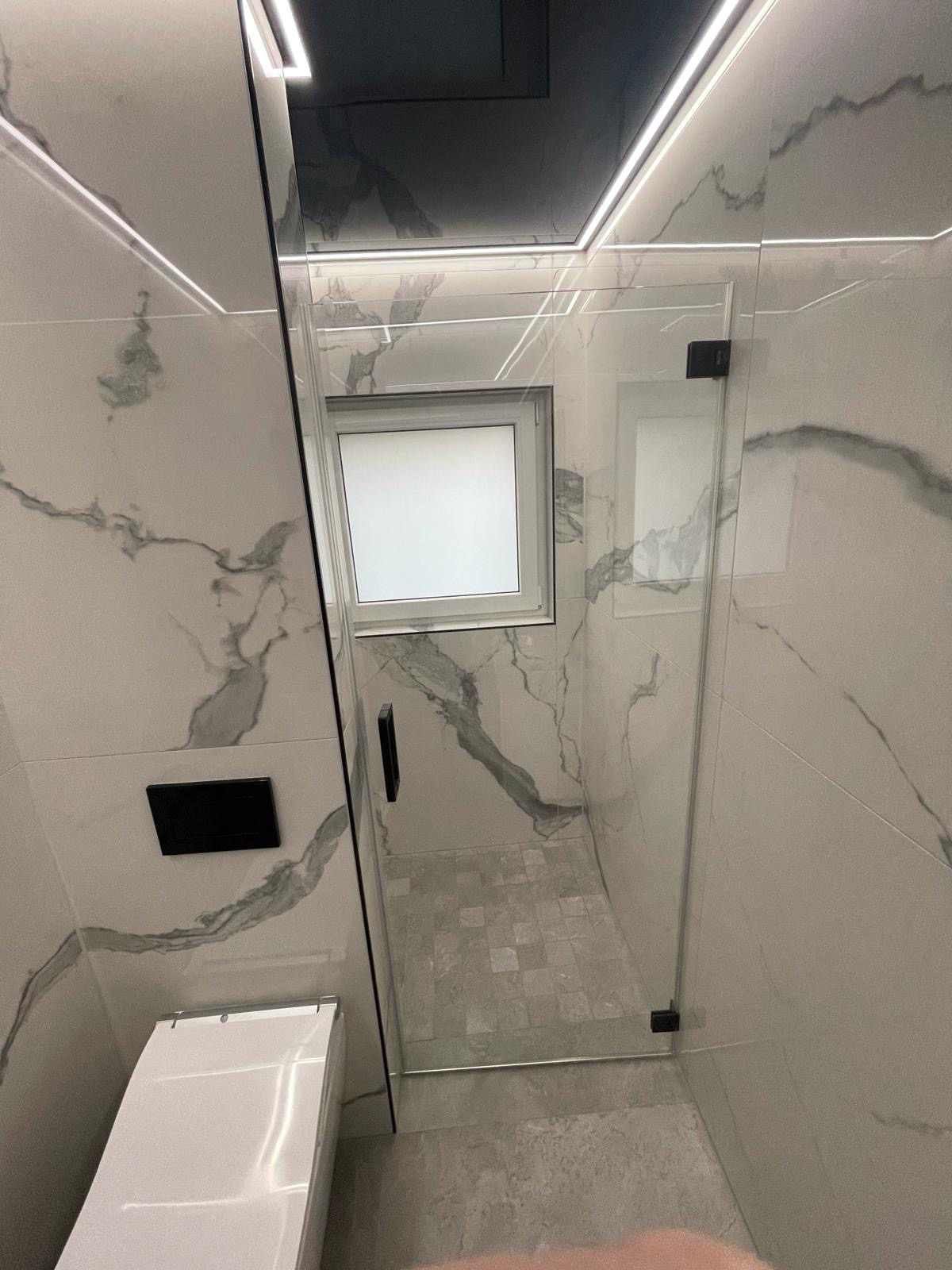 Ein Badezimmer mit Dusche, Glastür und Spiegel.