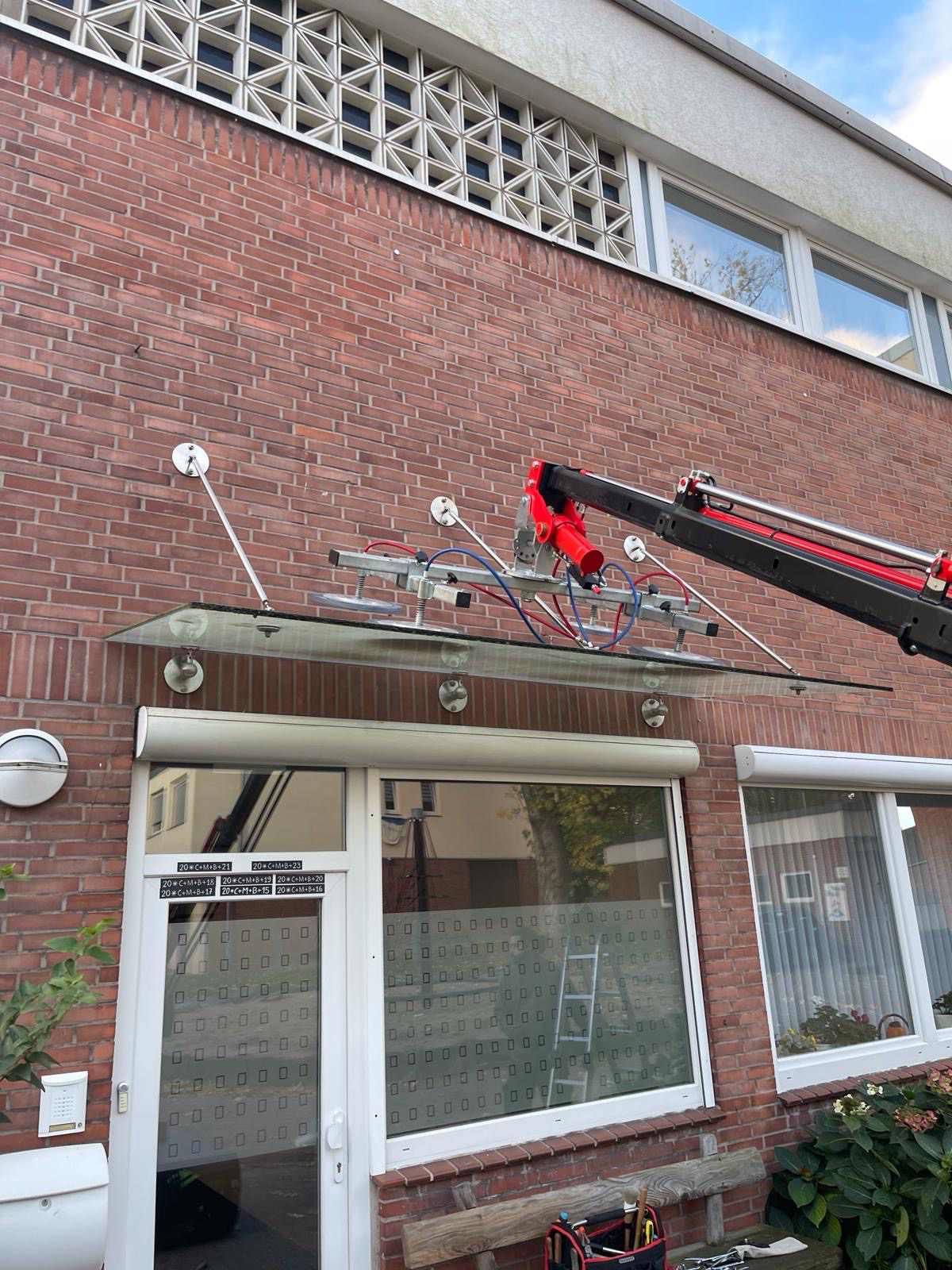 Ein Kran hebt ein Glasdach über ein Backsteingebäude.