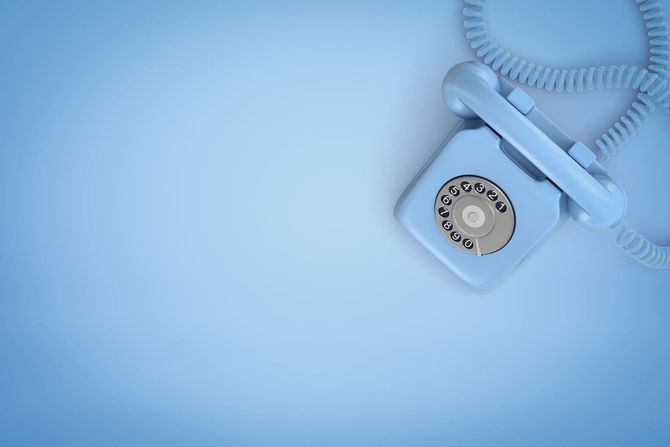 Un teléfono de disco de color azul claro reposa sobre un fondo azul a juego.