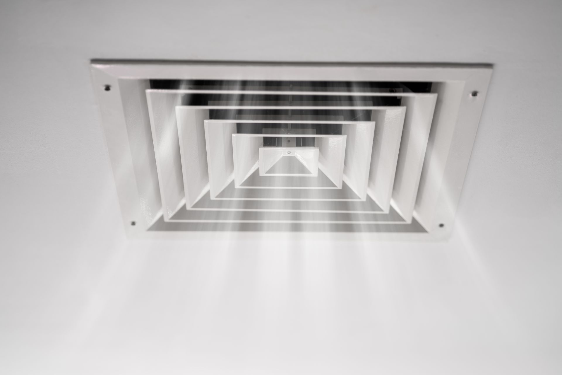 Grille d'aération blanche au plafond, vue d'en bas.