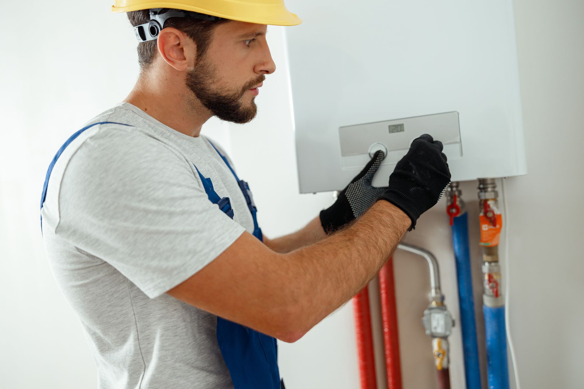 Un technicien inspecte un tableau électrique mural à l'aide d'outils dans une buanderie.