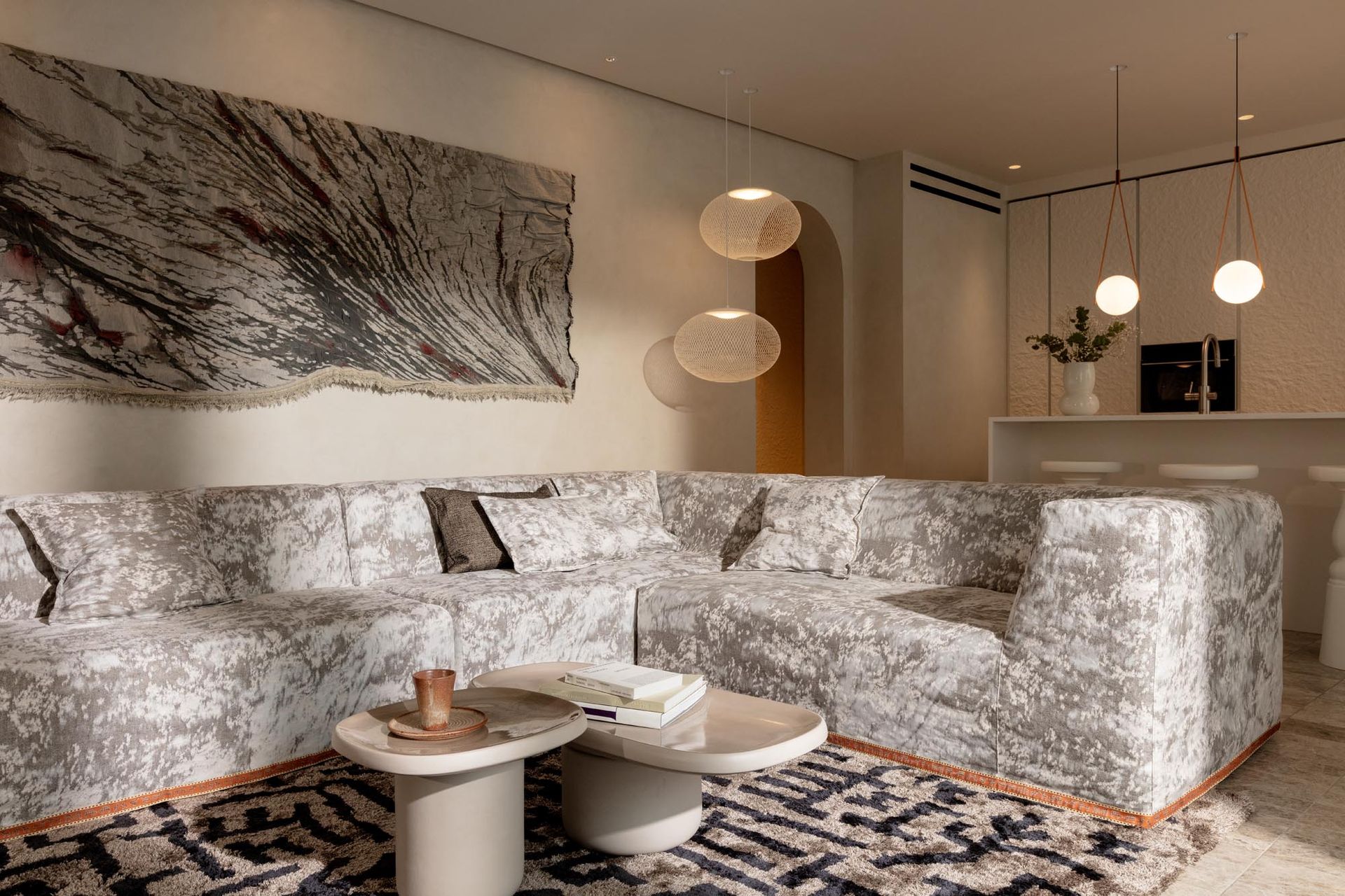 Wohnzimmer mit großem, strukturiertem Ecksofa, Couchtischen und abstrakter Wandkunst.