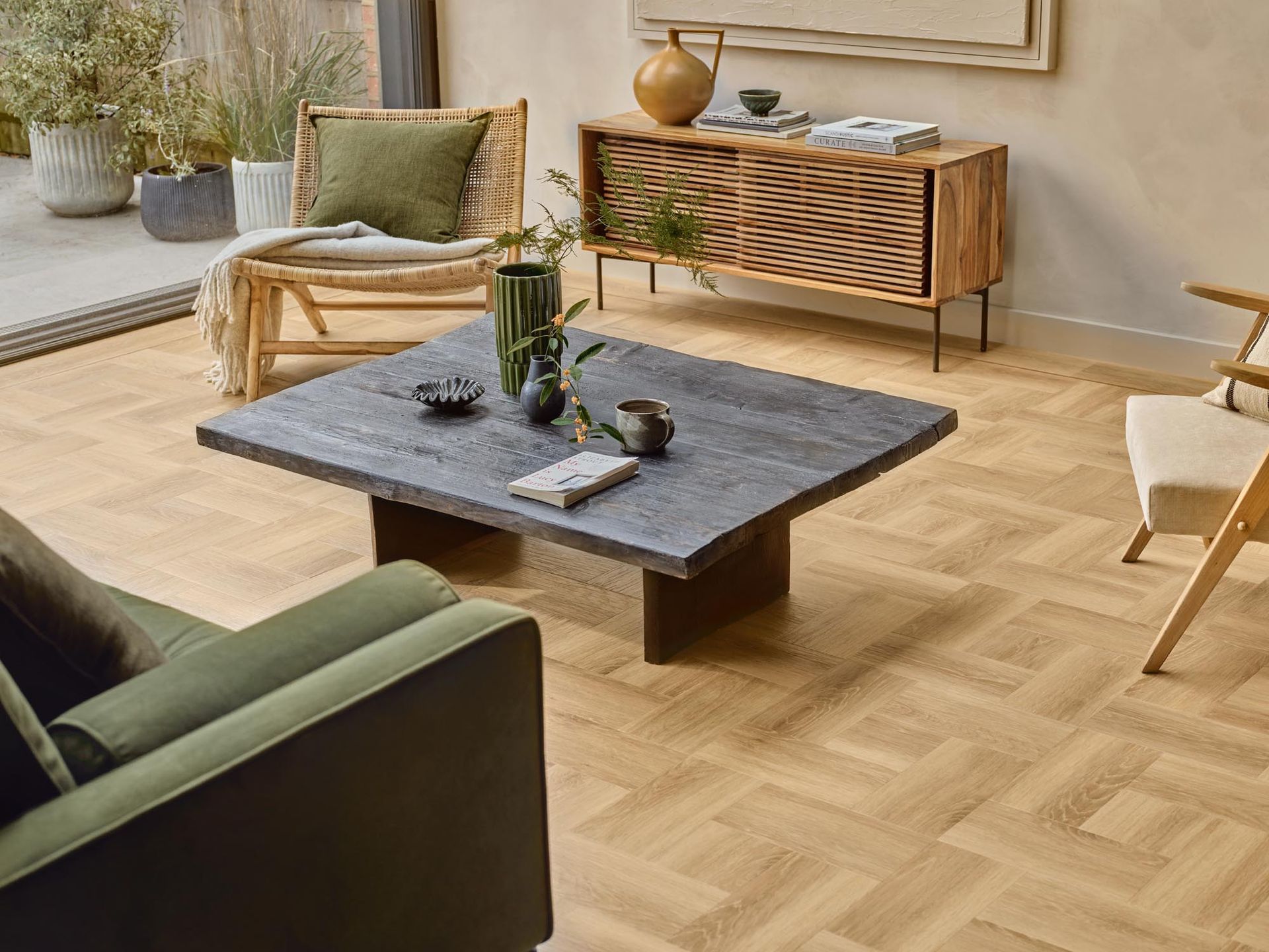 Wohnzimmer mit Holzboden, Couchtisch, grünem Sofa und Blick ins Freie.