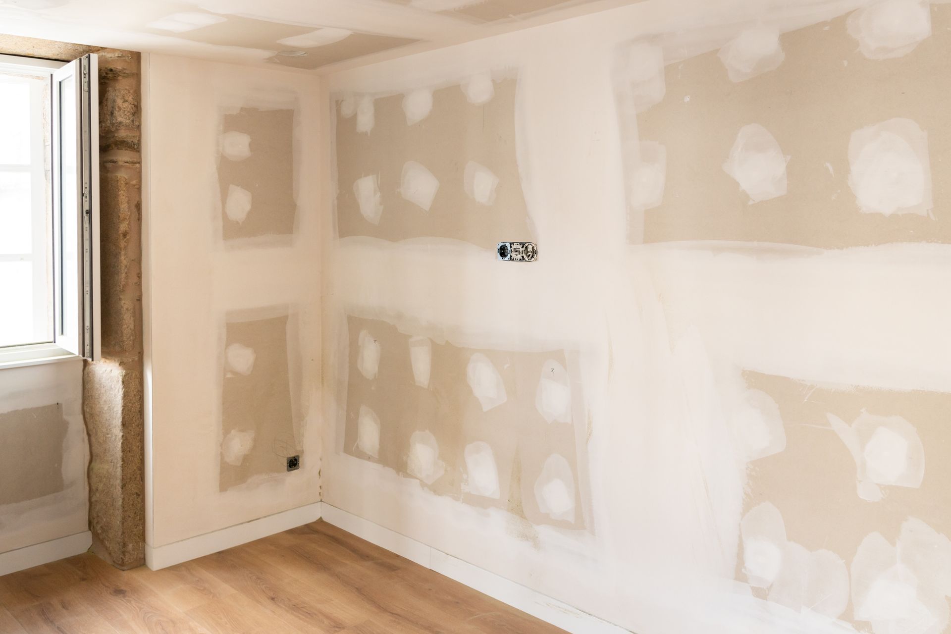 Une pièce vide avec des cloisons sèches, un parquet et une fenêtre.