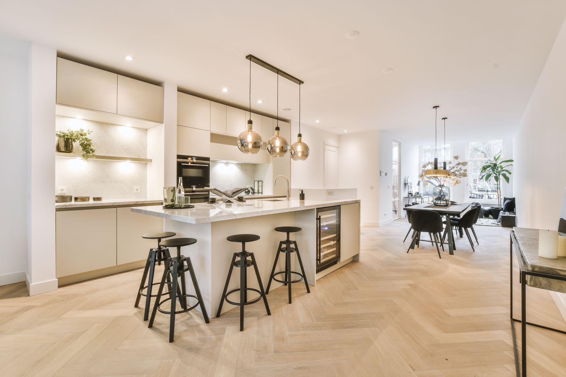 Une cuisine moderne et lumineuse avec un îlot central, des tabourets de bar et des suspensions lumineuses.