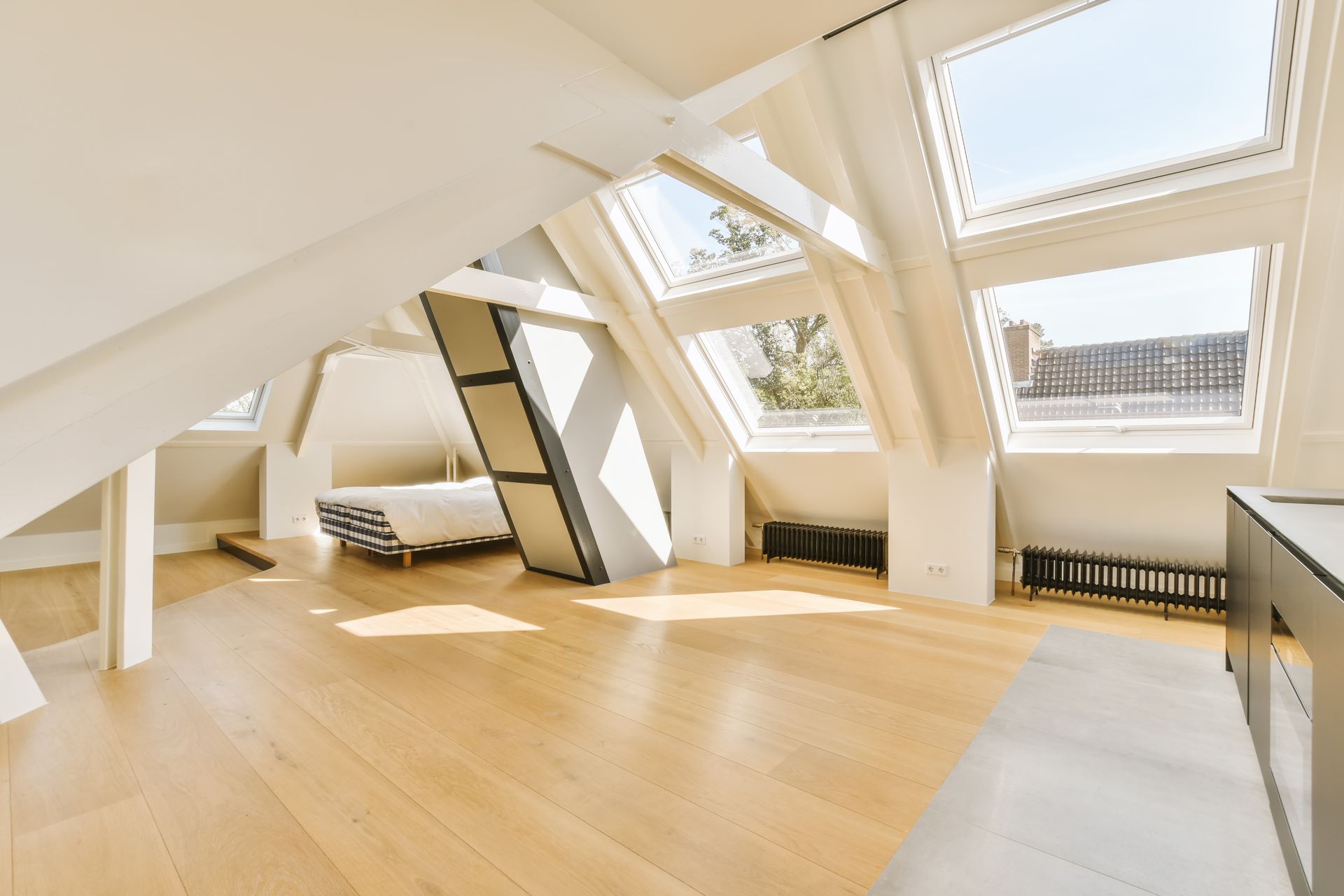 Une pièce mansardée lumineuse avec un parquet clair et des plusieurs fenêtres.