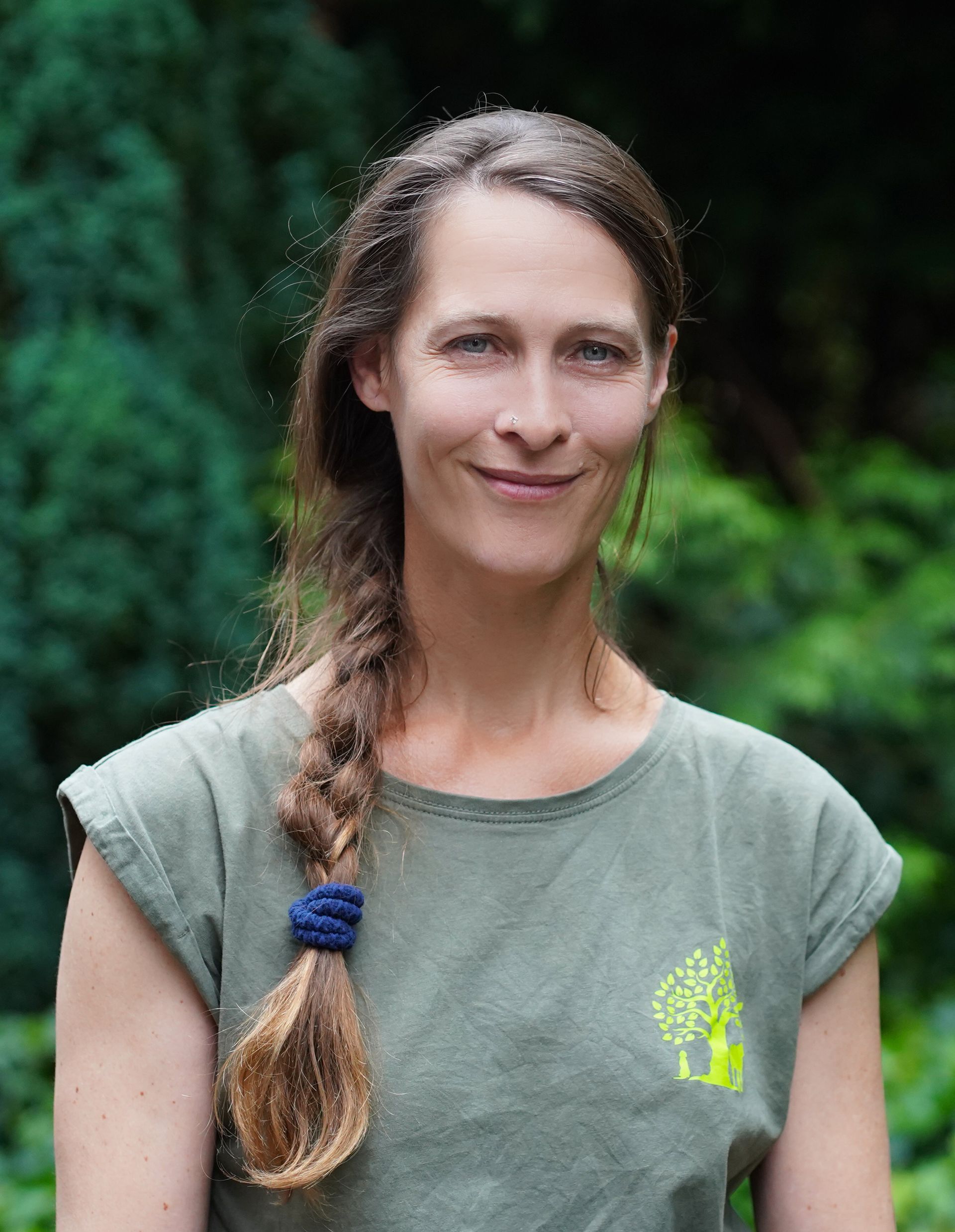 Eine Frau mit langen Haaren trägt ein grünes Hemd und lächelt.