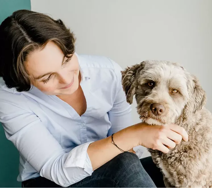 Eine Frau in einem blauen Hemd streichelt einen kleinen Hund
