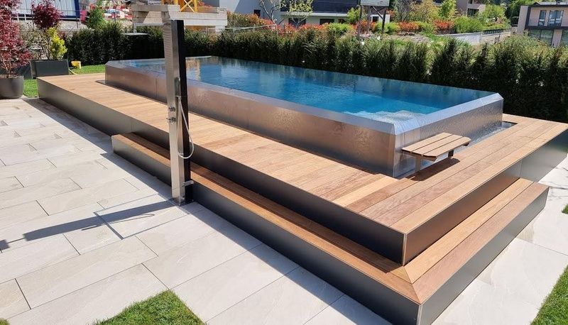 Auf einem Holzdeck befindet sich ein grosser Swimmingpool aus Edelstahl. Foto von der Artmetal GmbH